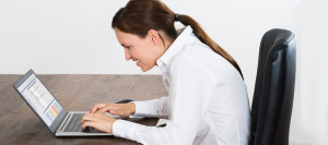 photo of woman sitting hunched over laptop